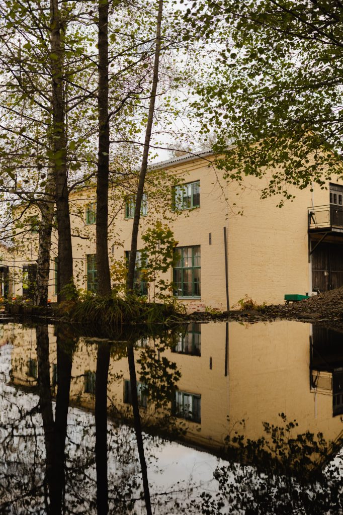 Historiallinen karkaisimo rakennus Mathildedalissa puron vastarannalla. Kuvassa näkyy myös rakennuksen heijastus purosta.