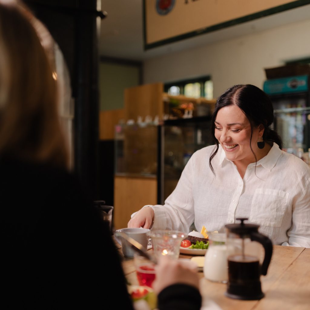 Nainen valkoisessa kauluspaidassa aamiaisella Café Mathildedalissa.