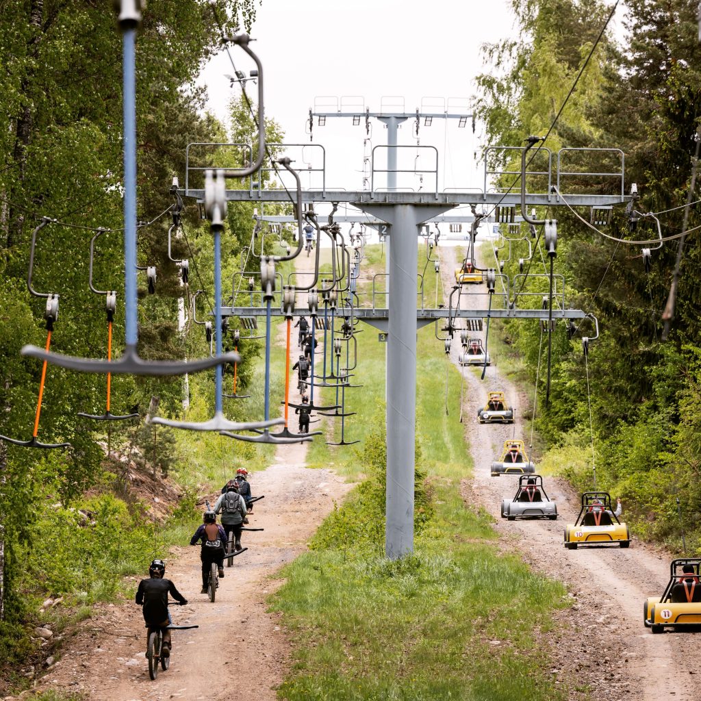 Ankkurihissi, jonka vasemmalla puolella kulkee alamäkipyöräilijöitä mäen huipulle ja oikealla puolella alamäkiautoja.