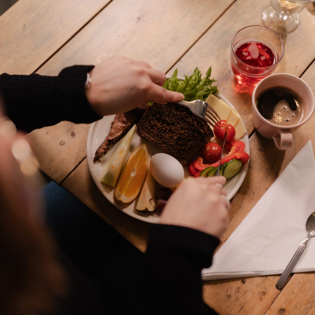 Hotel & Café Mathildedalin aamiaislautanen. Lautsella leipää, hedelmiä, kasviksia, juustoa ja leikkeleitä sekä pieni pala suklaakakkua.