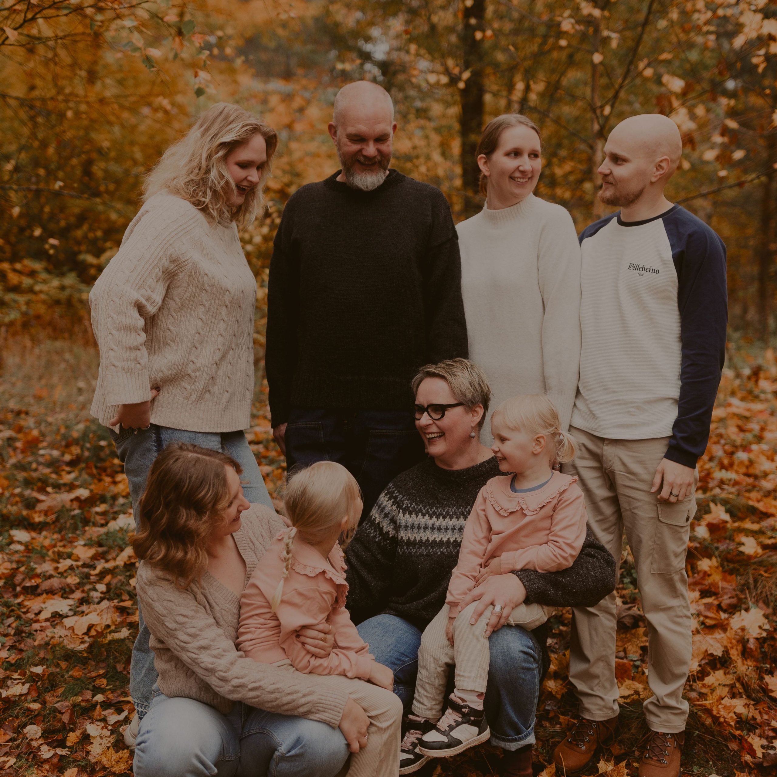 Kahdeksan henkinen perhe yhteiskuvassa syksyisessä maisemassa. Kuvassa on vanhemmat, lapset ja lapsenlapset.