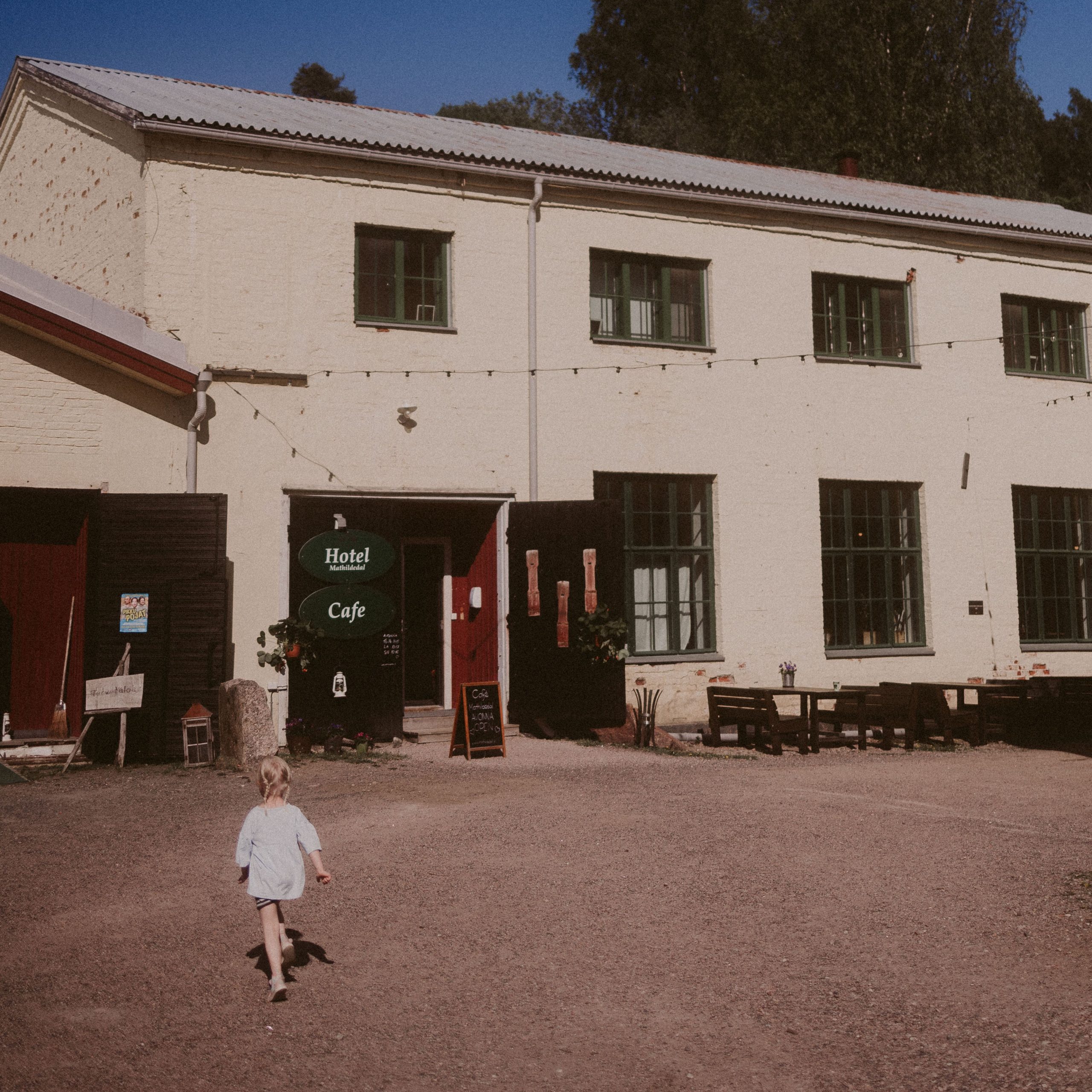 Lapsi juoksee kohti Café Mathildedalin sisäänkäyntiä kauniina kesäpäivänä.