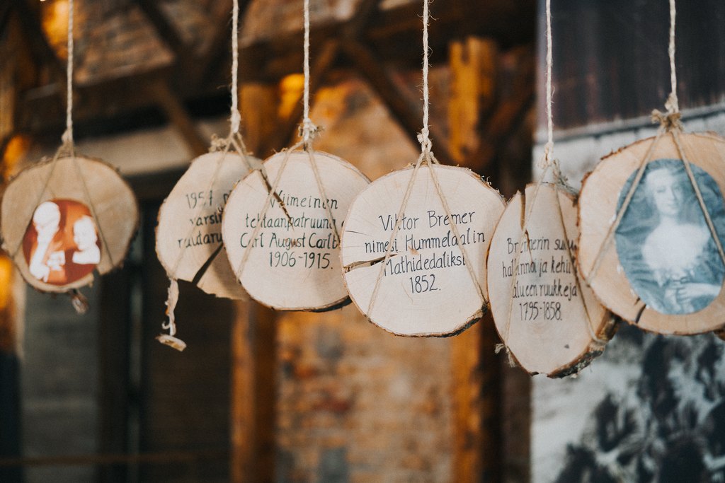 Mathildedalin Historianäyttelyssä riippuvat puiset elementit, joihin on kirjattu Teijon ja Mathildedalin ruukinpatruunat.