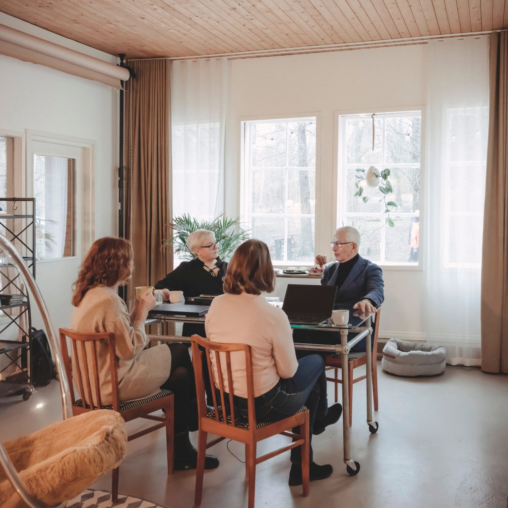 Kolme naista ja mies istumassa pöydän ympärillä Studiotilassa pitämässä palaveria.