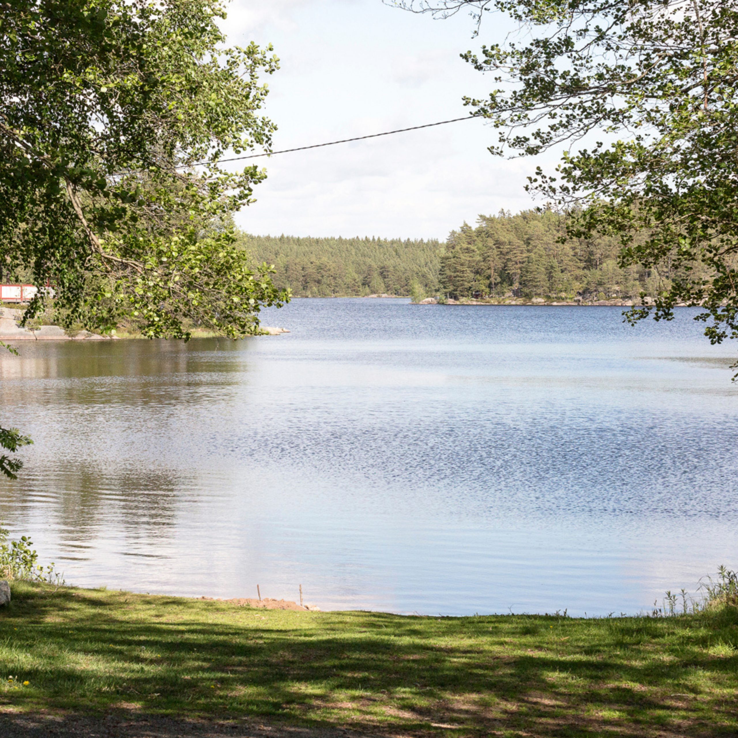 Pieni luonnon uimaranta Matildanjärven rannalla. Puut kehystävät järvimaisemaa.
