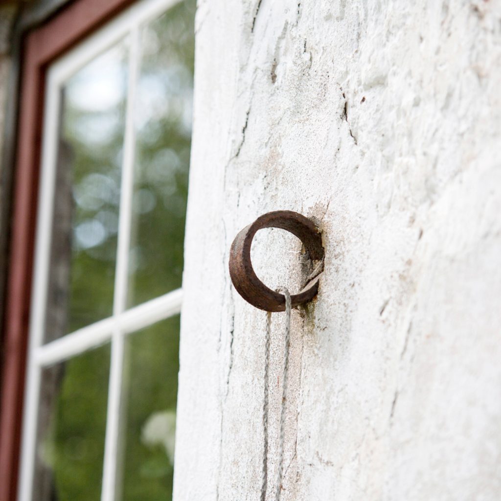 Rautainen rinkulan mallinen yksityiskohta vanhassa kivirakennuksessa. Taustalla näkyy saman rakennuksen ikkuna.